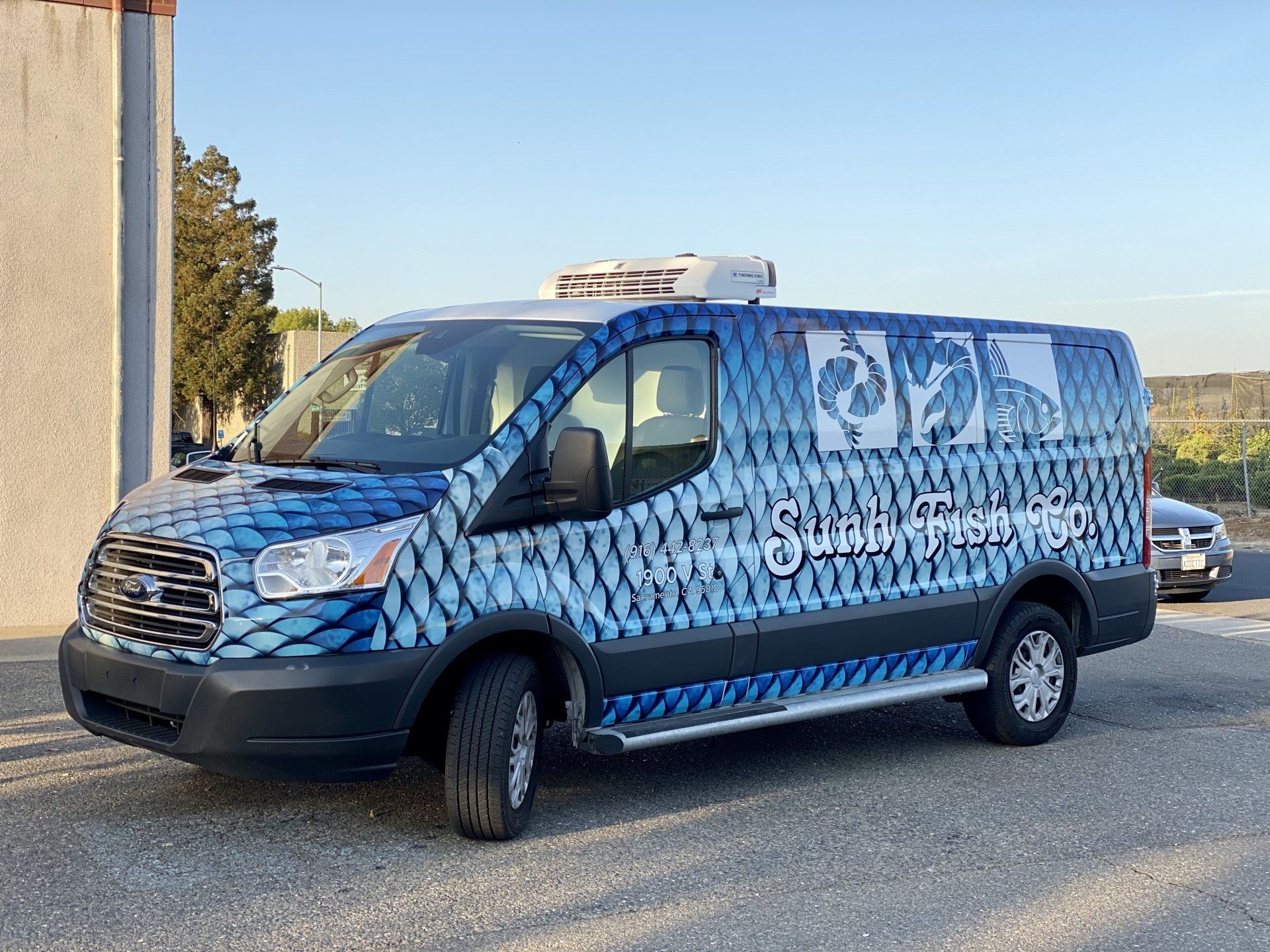 A blue and white van is parked in front of a building.