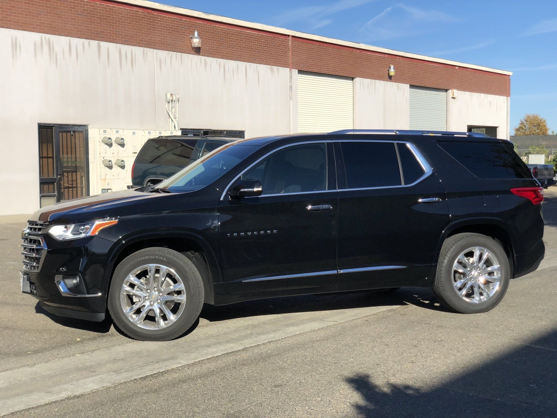 A black suv is parked in front of a building.