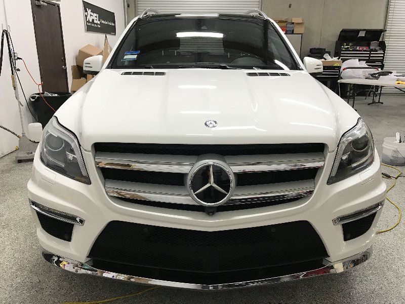 A white mercedes benz is parked in a garage.