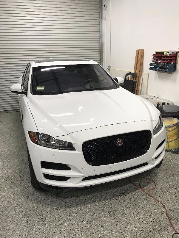 A white jaguar f type is parked in a garage.