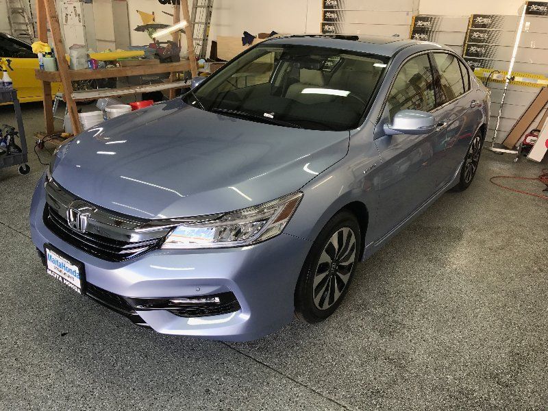 A blue honda accord is parked in a garage.