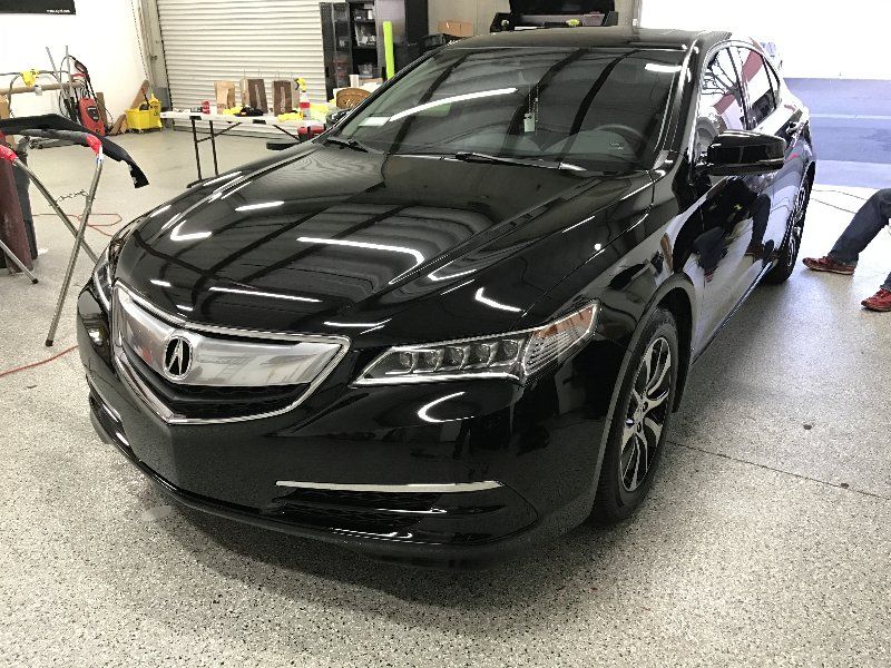 A black acura tl is parked in a garage.