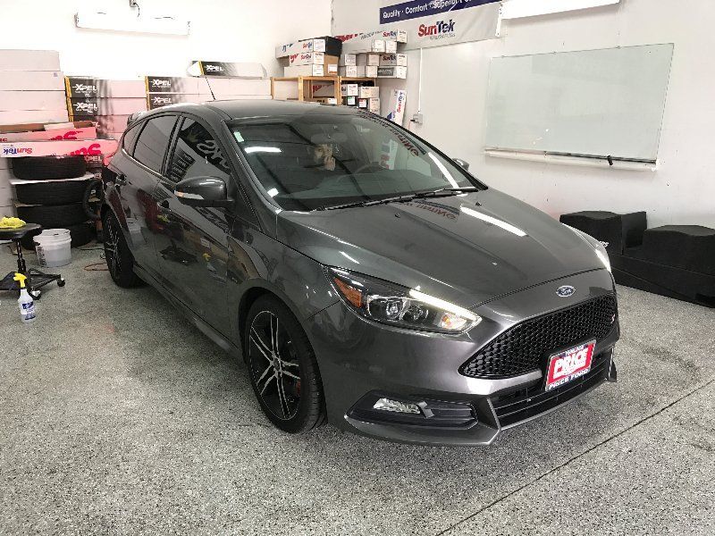 A gray ford focus is parked in a garage.