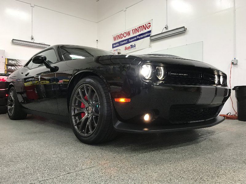 A black dodge challenger is parked in a garage.