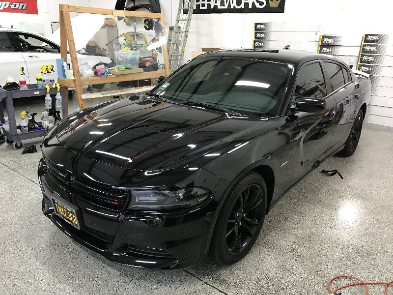 A black dodge charger is parked in a garage.