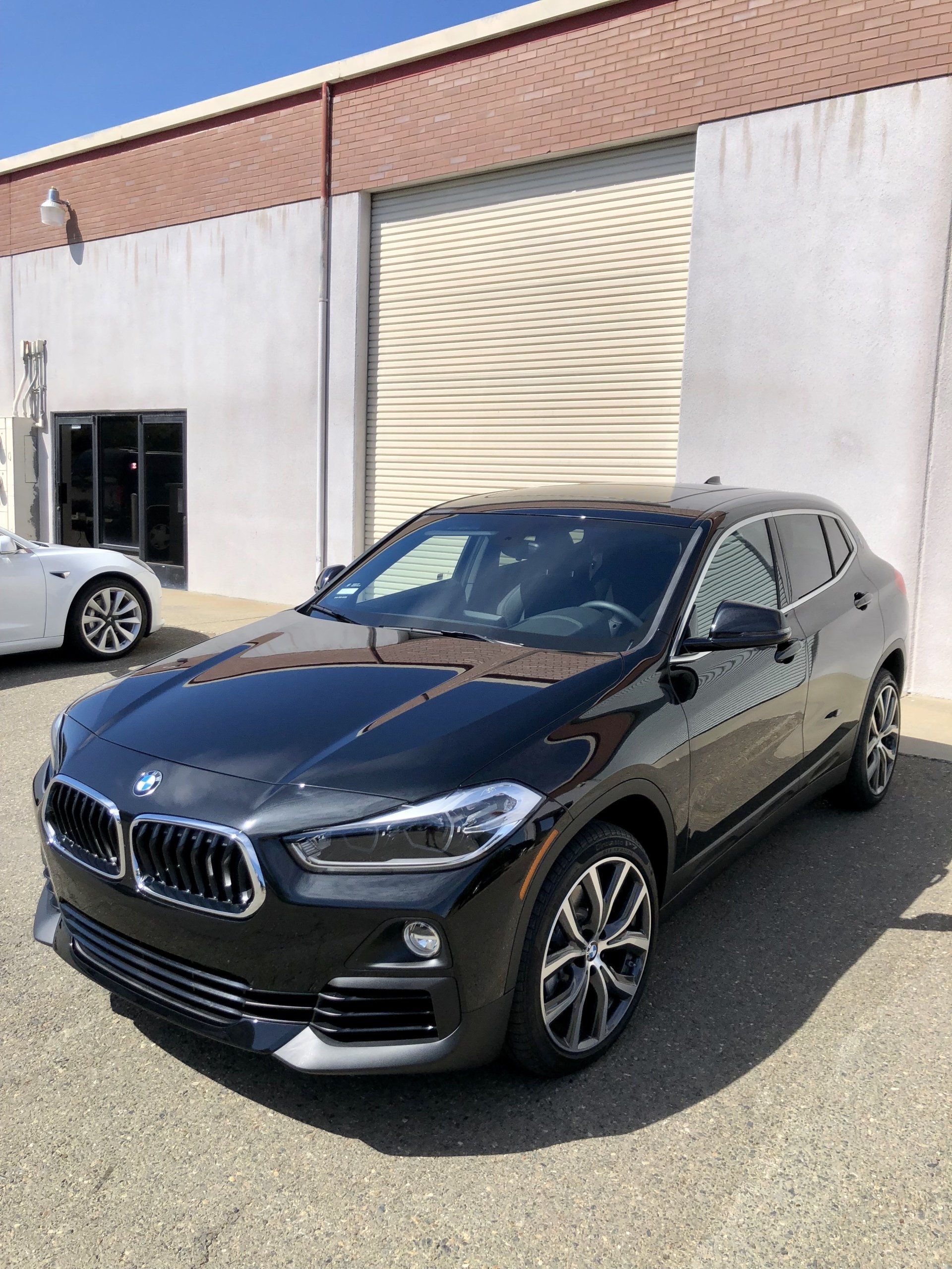 A black bmw x2 is parked in front of a building.