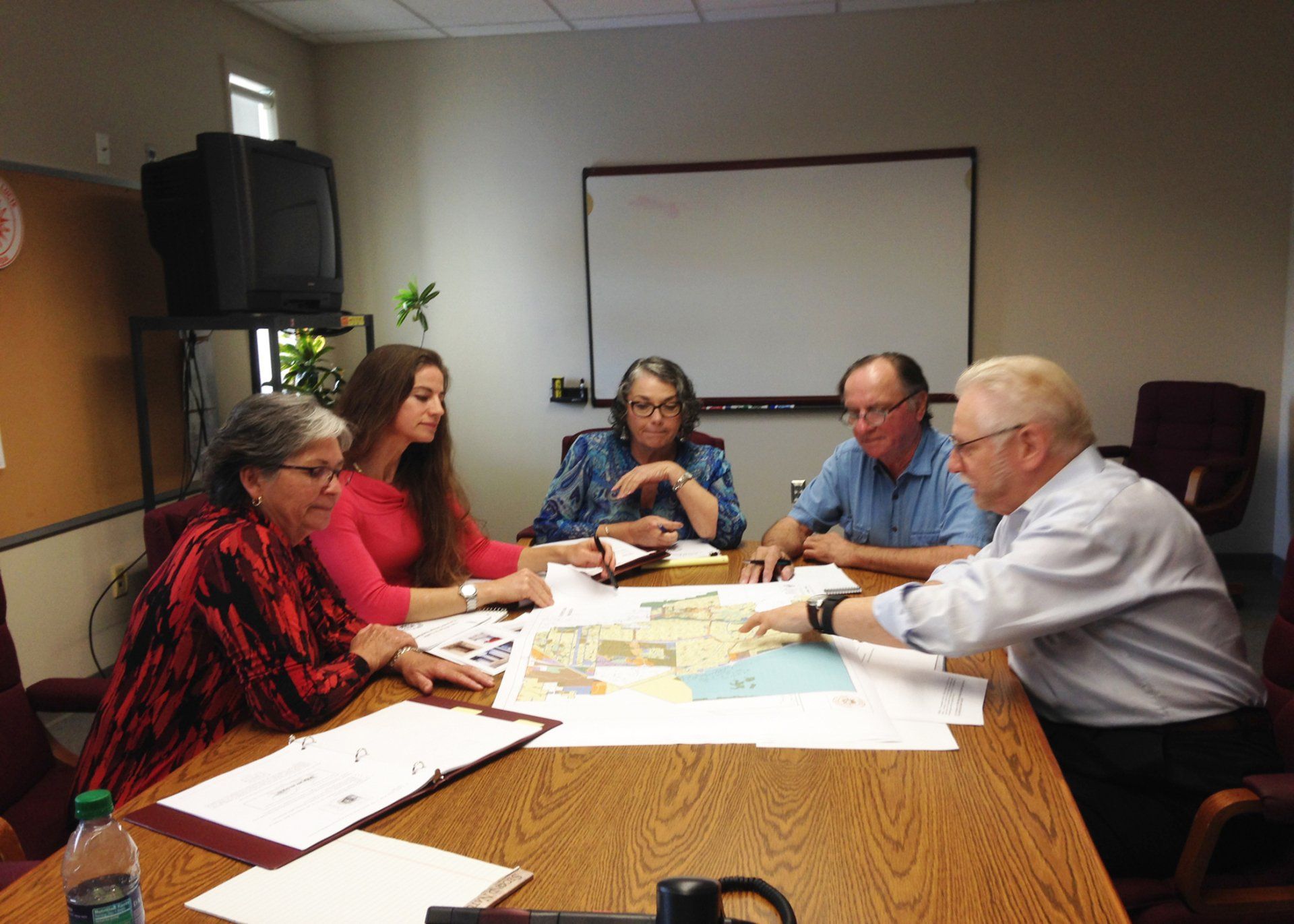a group of people are sitting around a table looking at a map .