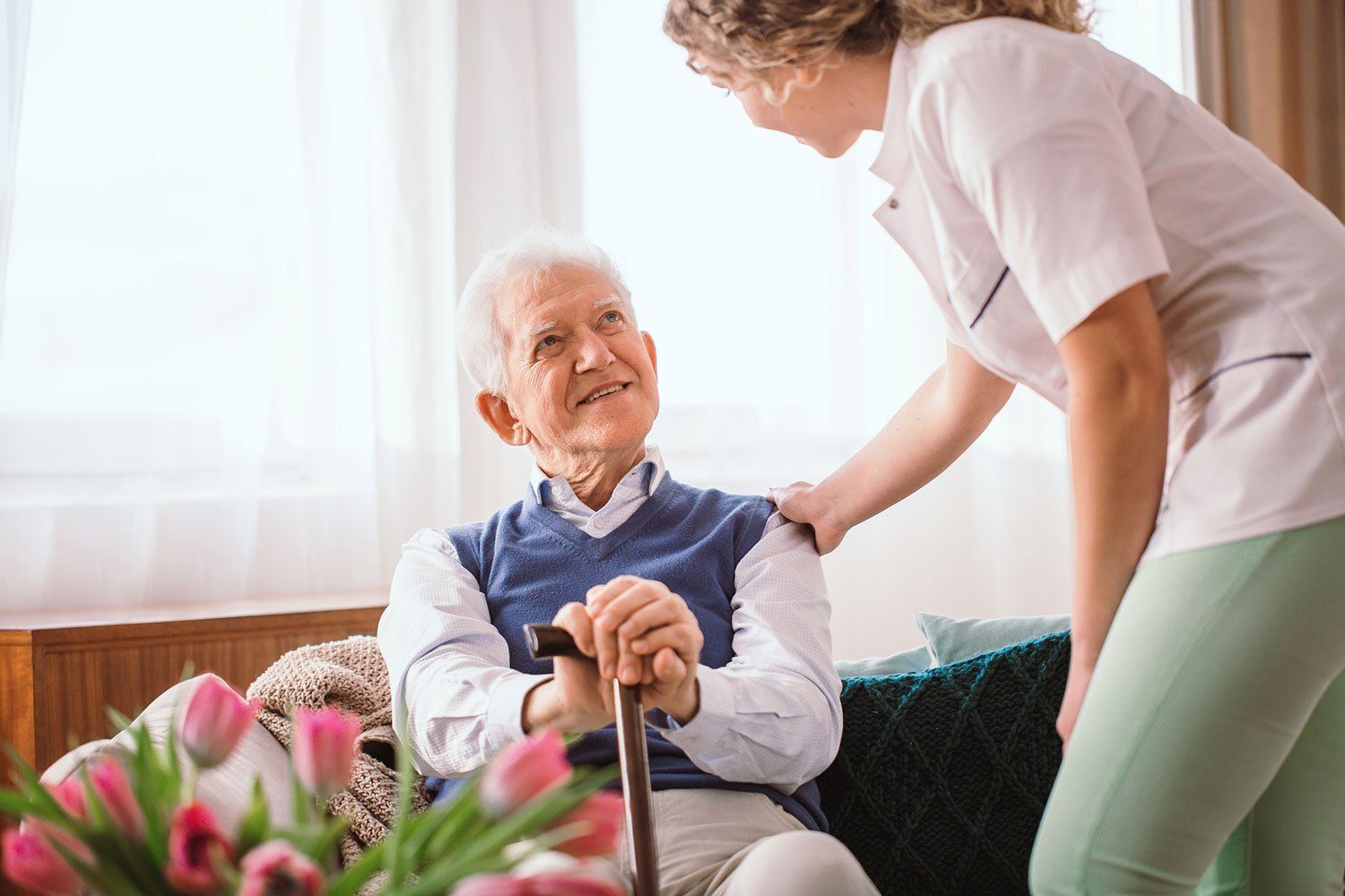Senior man with a walking stick being comforted by nurse