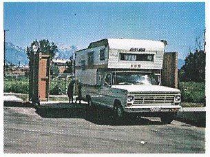 A white truck with a trailer attached to it is parked in a parking lot.