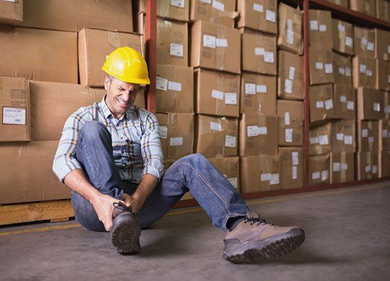 Worker with Sprained Ankle on Floor - Pain Therapy in Bellefontaine OH