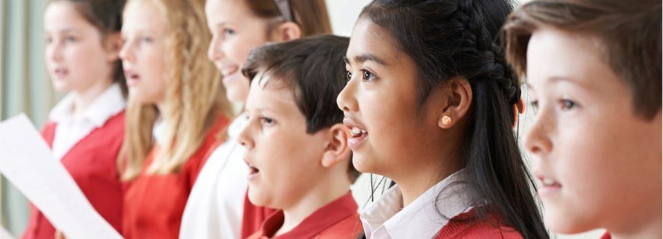 Kinderchor in rot weißen Outfits singt