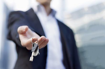 man holding out house keys