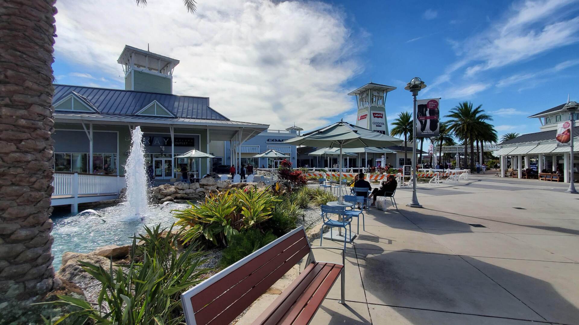 A bench is sitting in front of a fountain in a shopping mall.