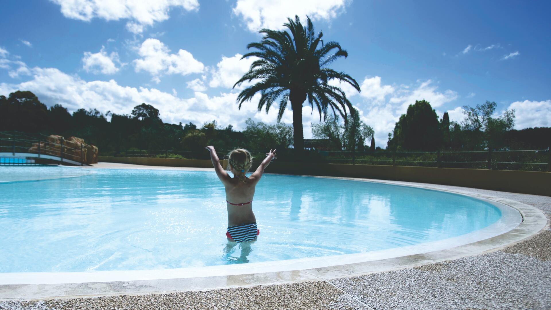 A young boy is jumping into a swimming pool.
