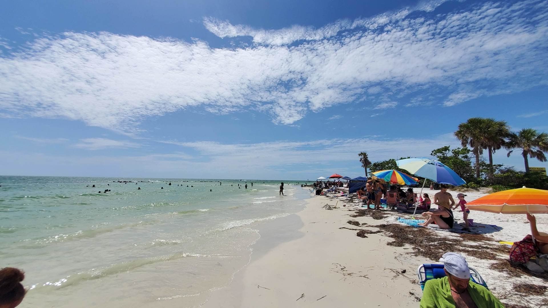 A beach filled with people and umbrellas on a sunny day.