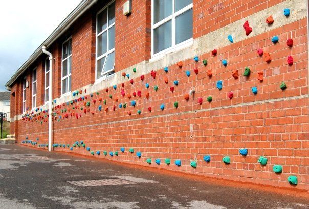 Brick building exterior with colorful climbing holds installed on the wall.