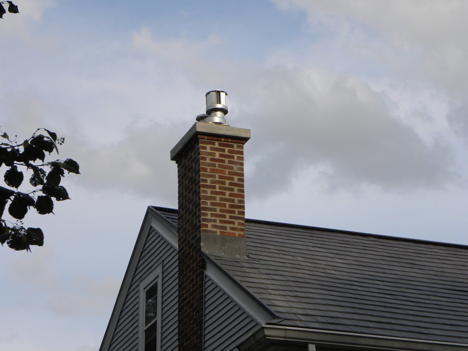 House roof with brick chimney against a cloudy sky