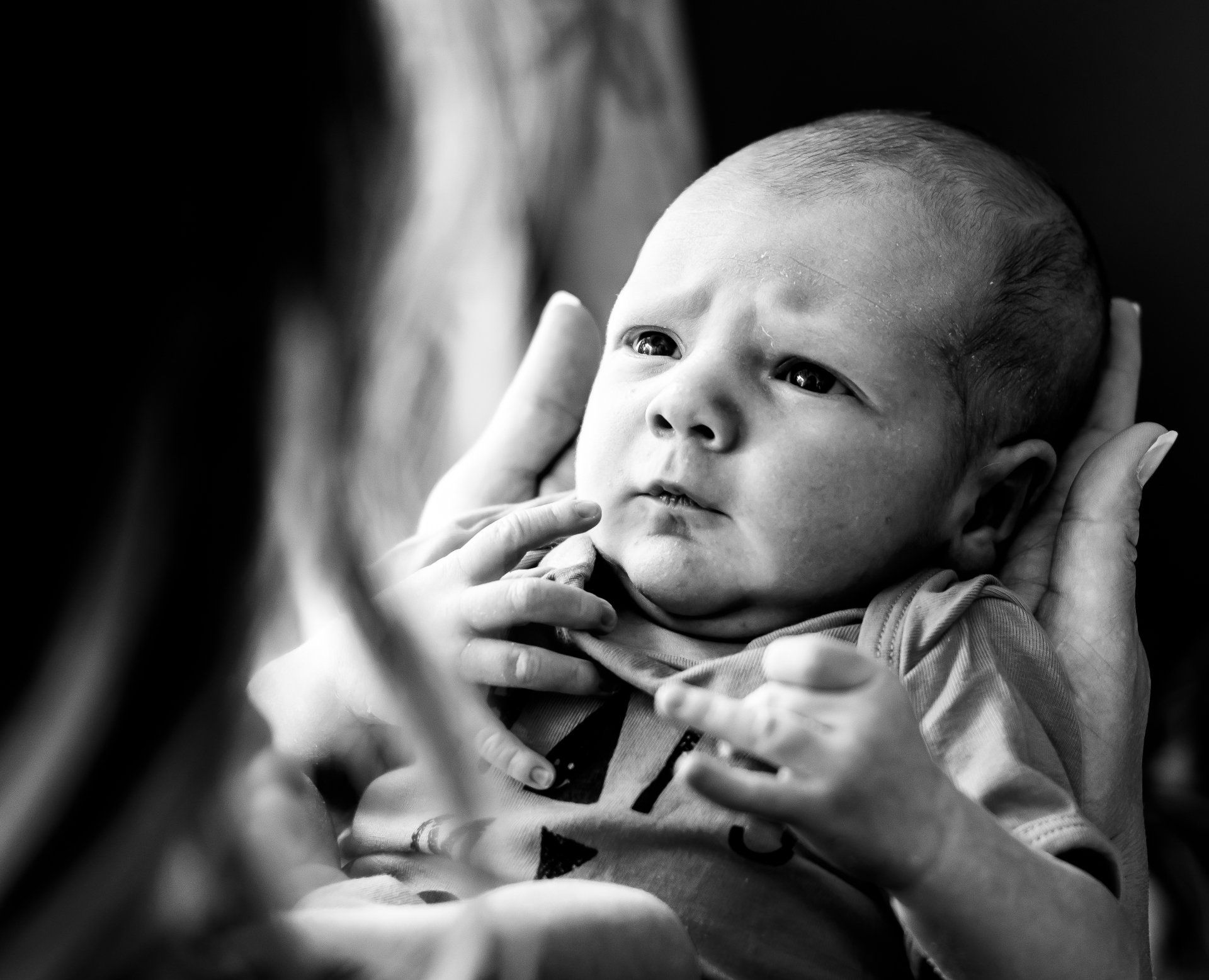 Baby in de armen, met een bezorgde blik, close-up, zwart-wit.
