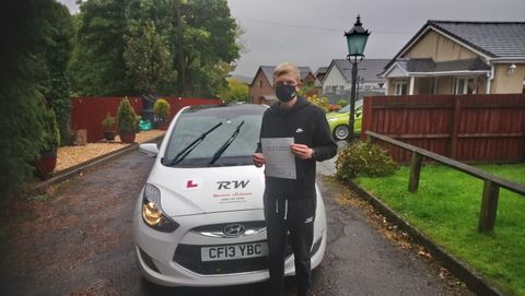 young man wearing mask holding driving test pass