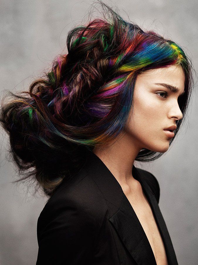 A woman with rainbow hair is wearing a black jacket.