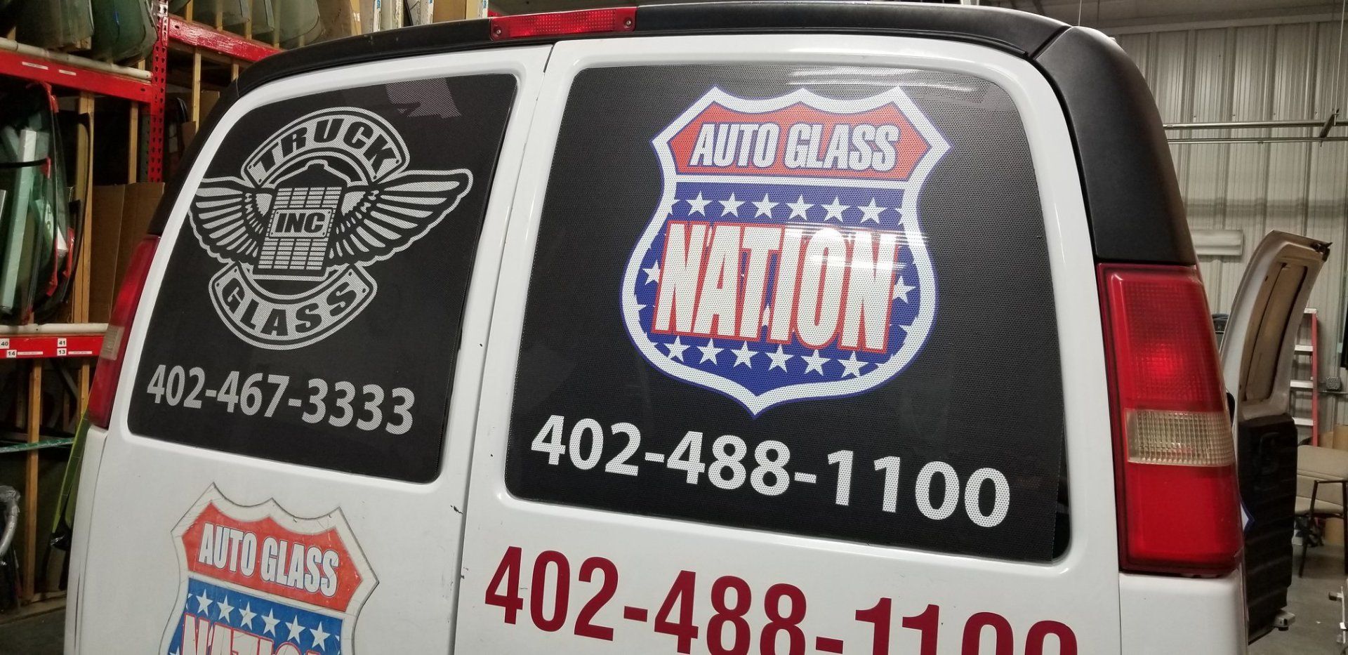 A white van with a sticker on the back window that says auto glass nation