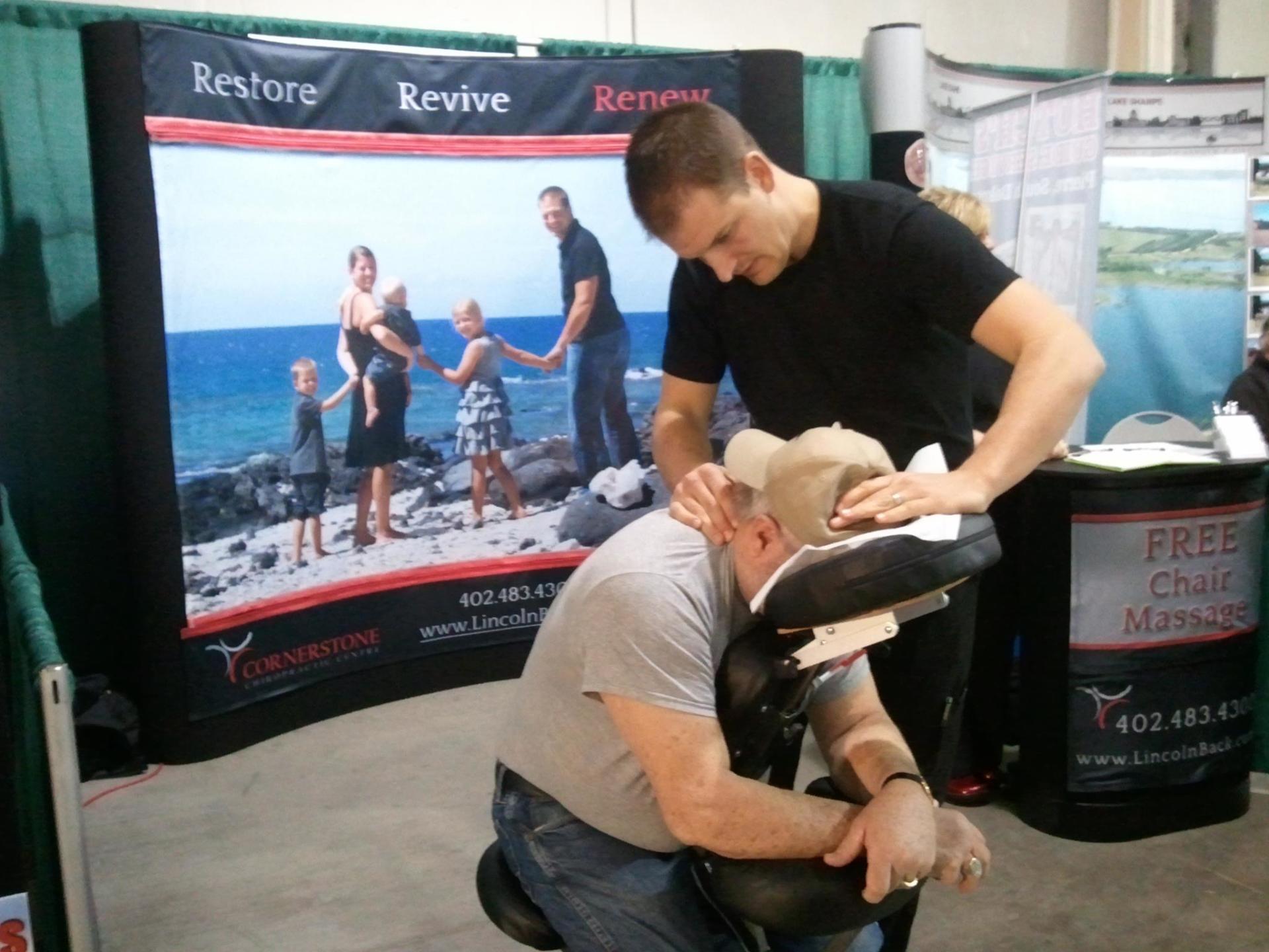 A man is getting a massage in front of a sign that says free chair massage
