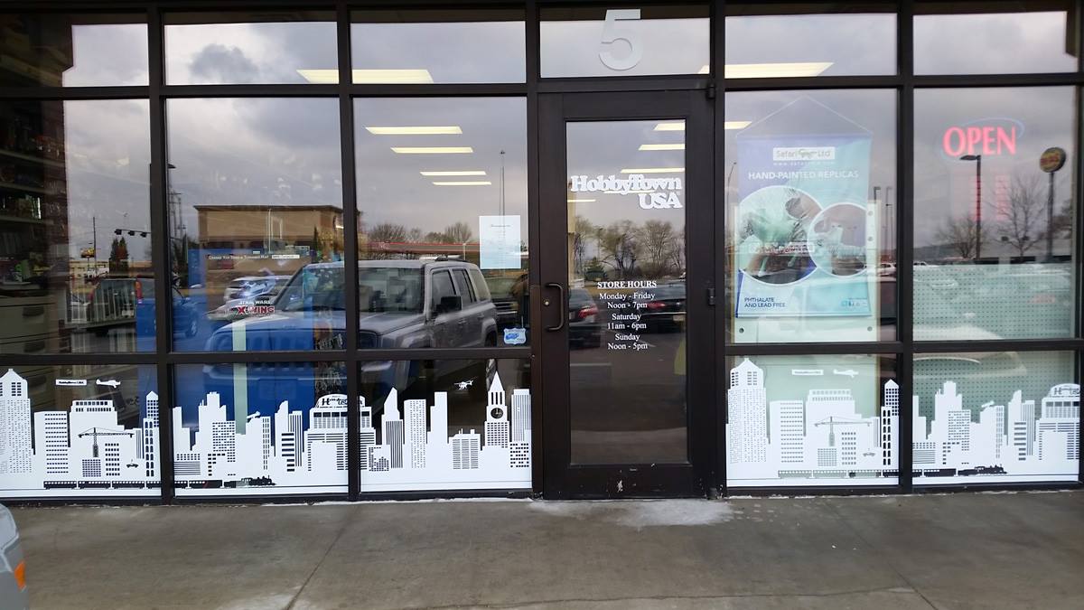A store front with a city skyline on the windows.