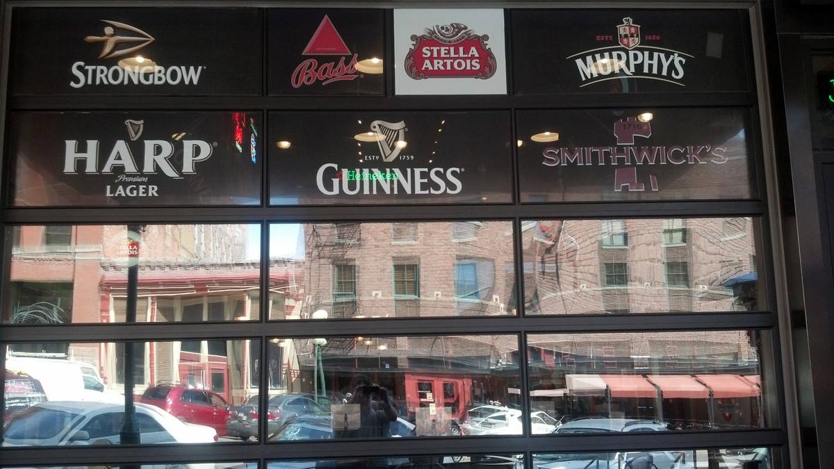 A store front with signs for harp guinness and strongbow