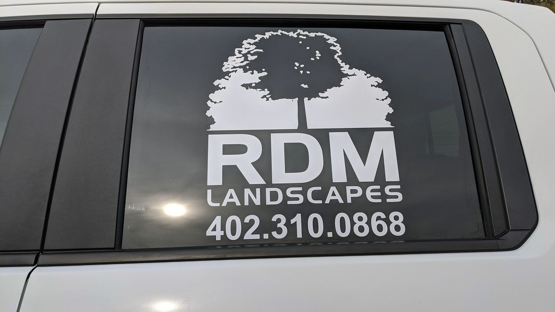 A white van with a rdm landscapes logo on the back window