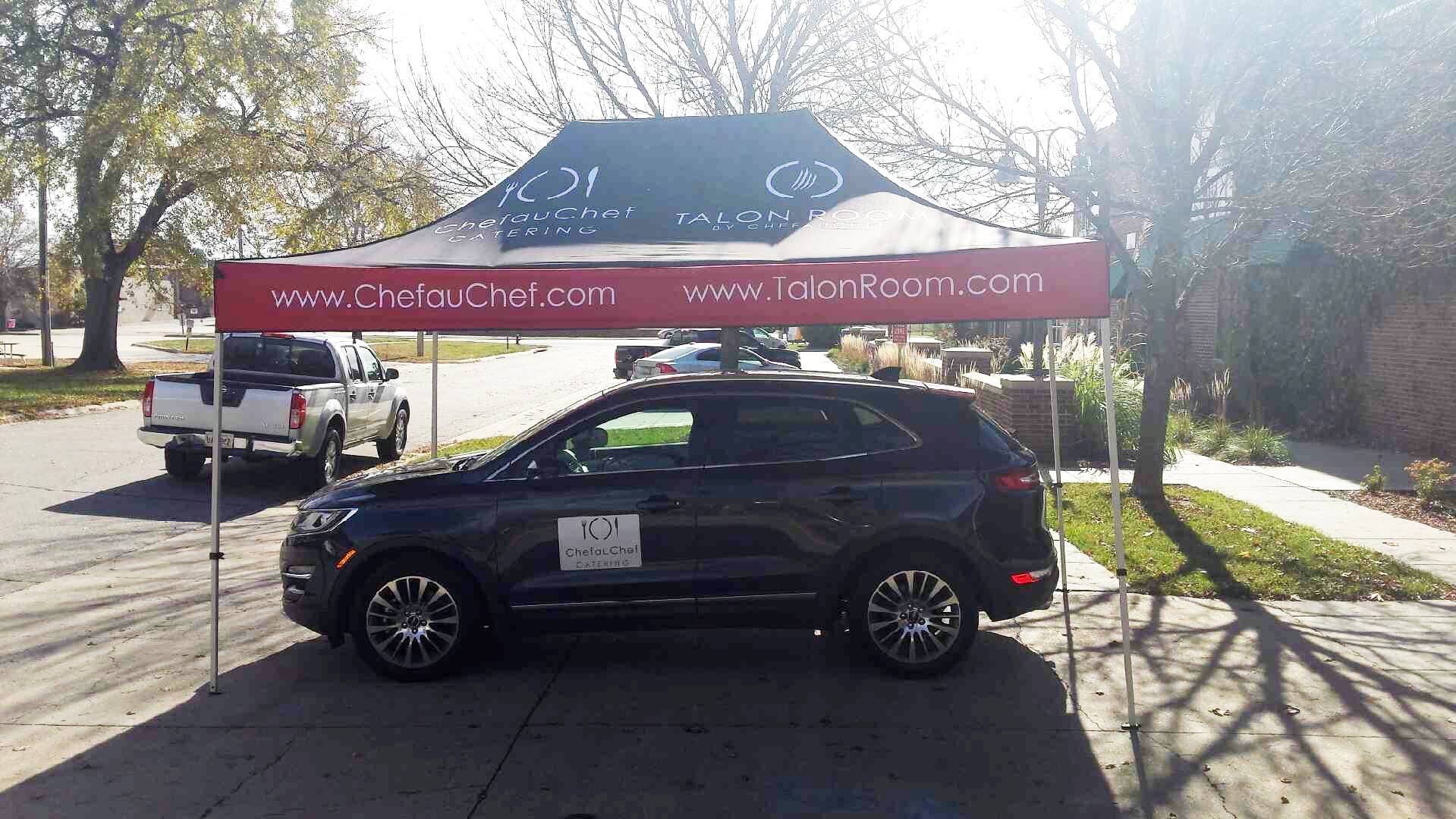 A car is parked under a canopy that says ' chelseahotel.com ' on it