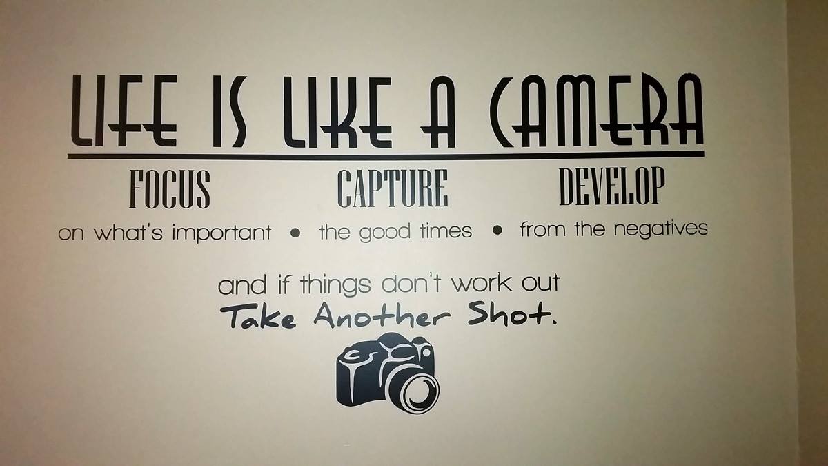A sign on a wall that says life is like a camera