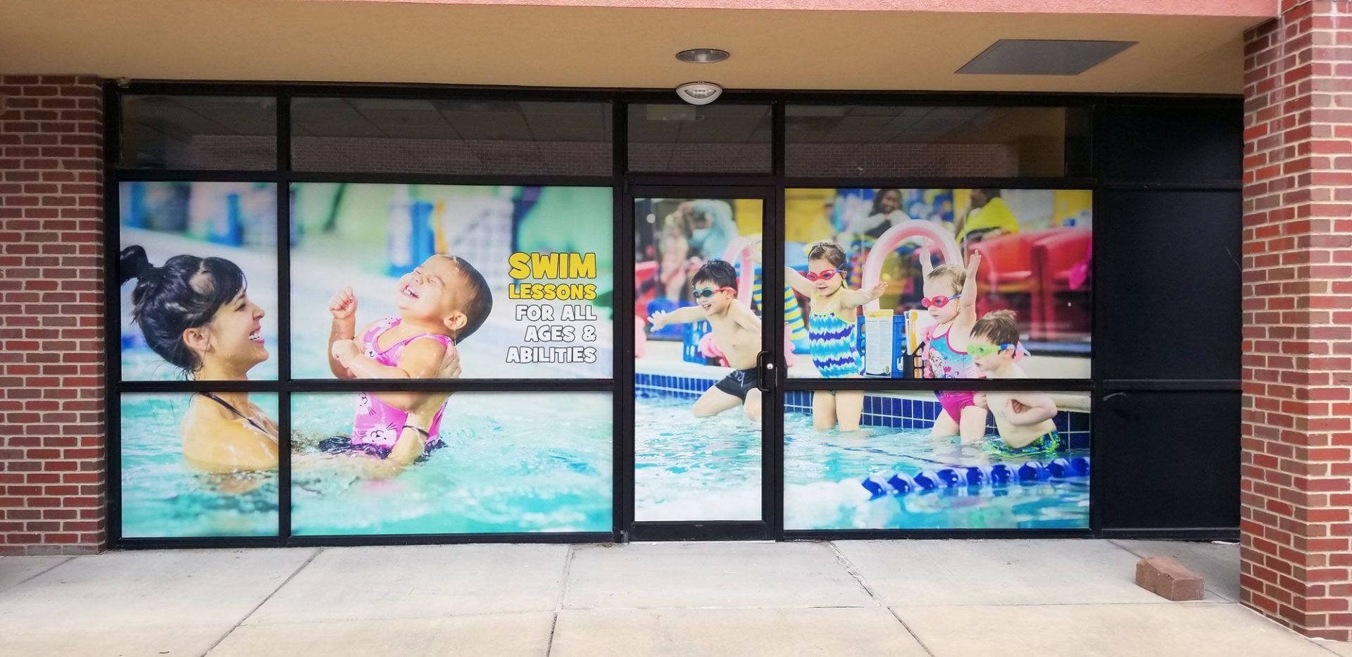 A window with a picture of a woman holding a baby in a pool.