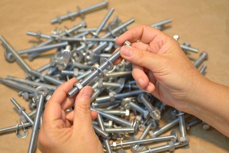 Man Inserting Washer And Nuts On A Bolt — Springfield, MI — Schweitzer Bros. Inc
