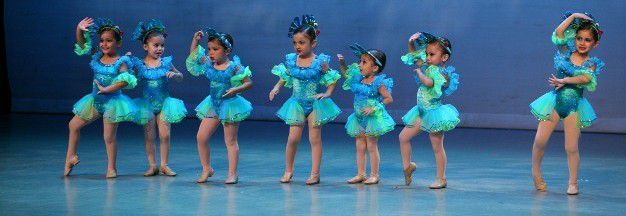 A group of young girls are dancing on a stage.