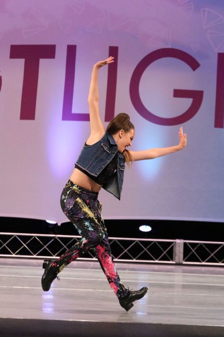 A woman is dancing in front of a sign that says tlige