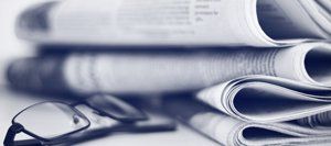 A stack of newspapers and glasses on a table.
