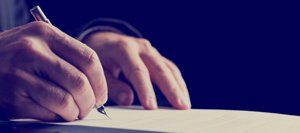 A person is writing on a piece of paper with a pen.