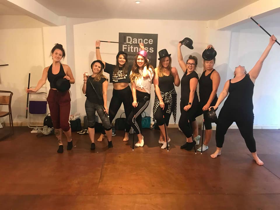 Hen party group performing a 1920s Charleston dance routine in a studio, holding canes and top hats in a lively vintage themed class