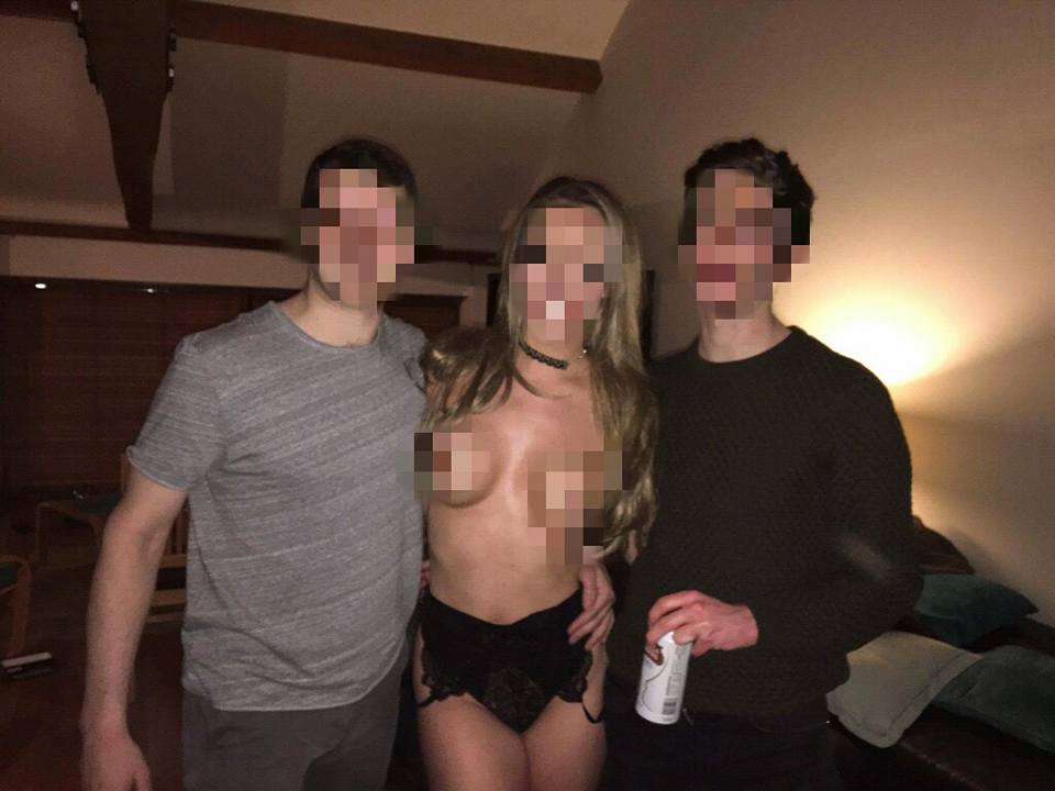 Group photo at a private party showing an adult female entertainer wearing lingerie standing between two adult guests in a living room setting, with faces obscured for privacy.