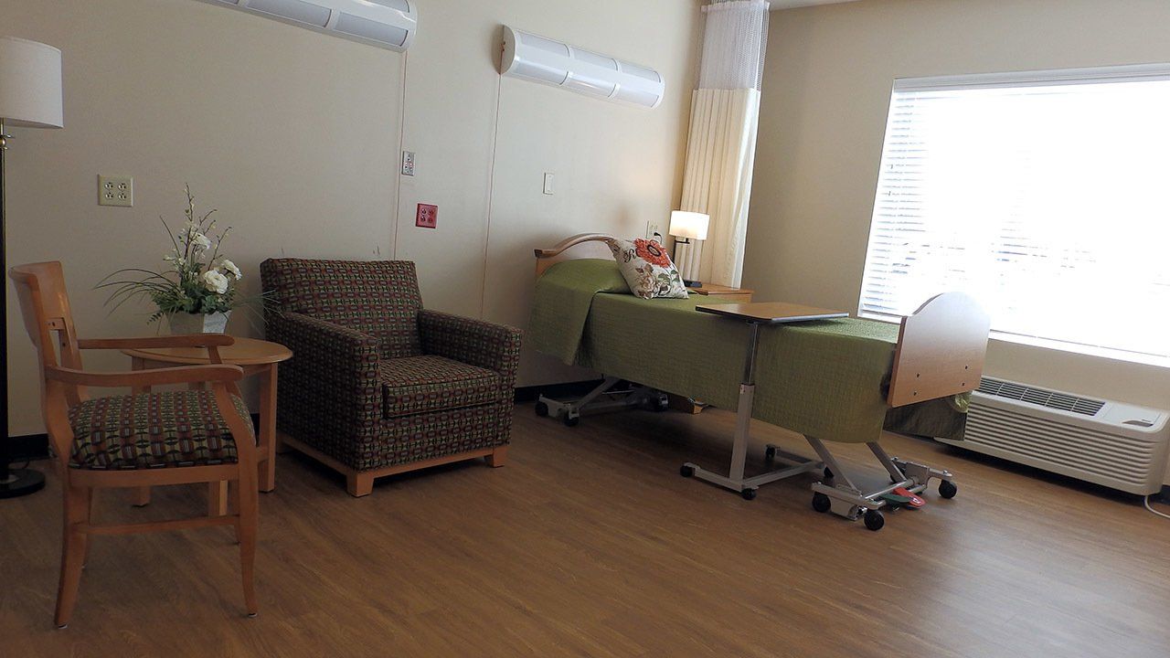 A hospital room with a chair a table and a bed