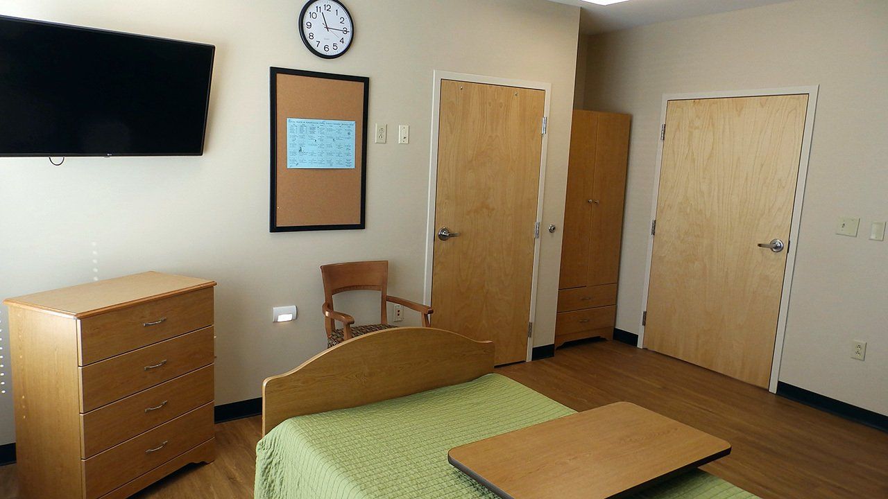 A bedroom with a bed a dresser and a flat screen tv