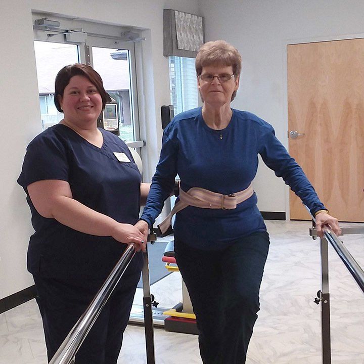 Two women are standing next to each other on a set of parallel bars.