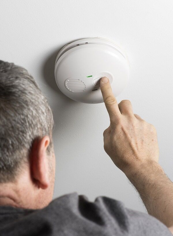 An Electrician Activates Smoke Alarm — Electrician in Newtown, QLD An Electrician Activates Smoke Alarm — Electrician in Newtown, QLD