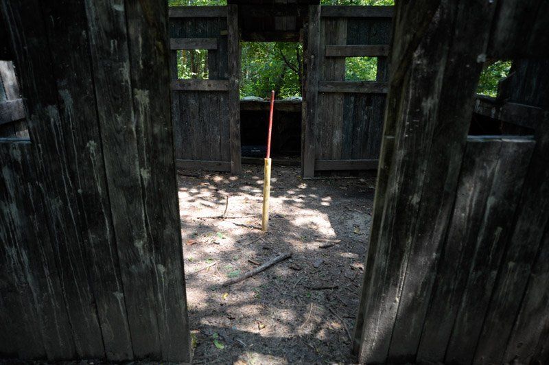 A wooden fence with a red stick sticking out of it.