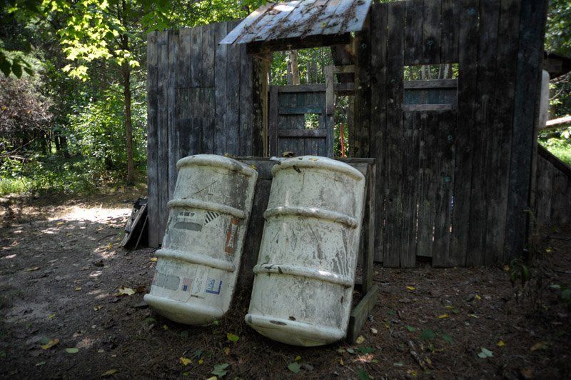 Two white barrels are sitting in front of a wooden building.