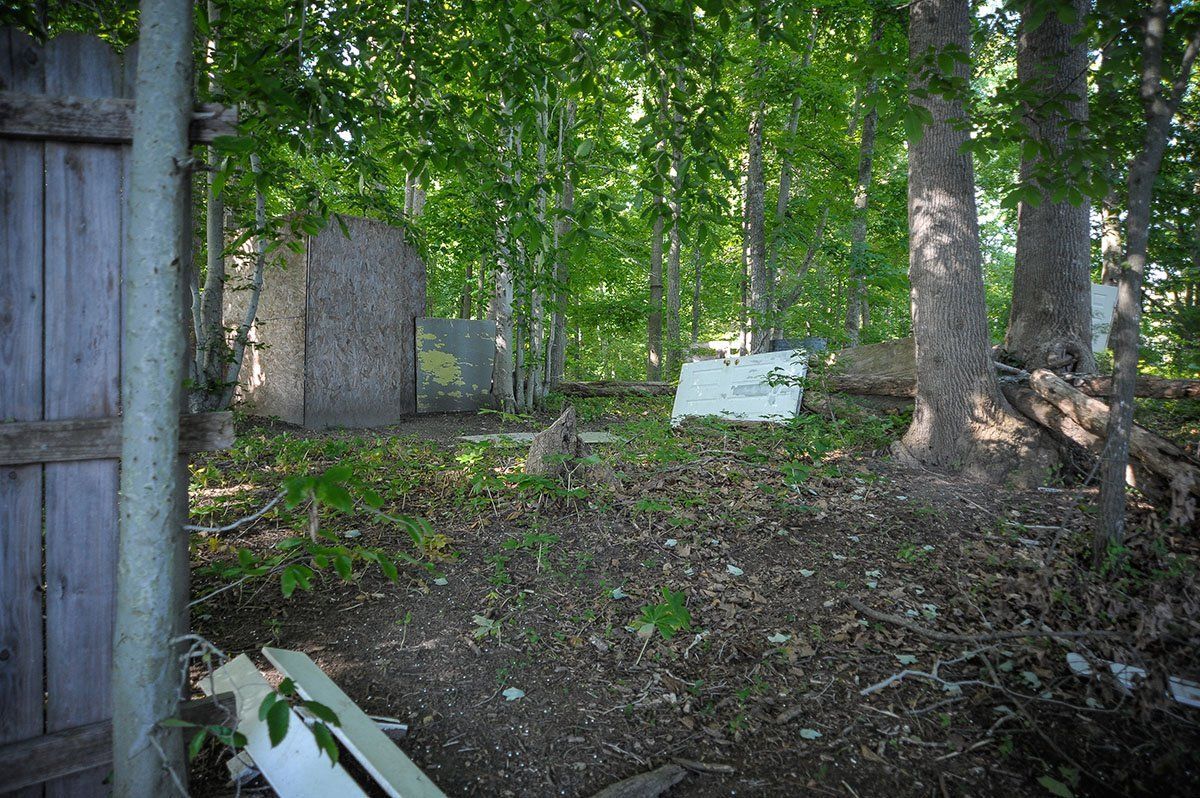 Hogan's Alley Field A wooden fence is surrounded by trees in a forest.