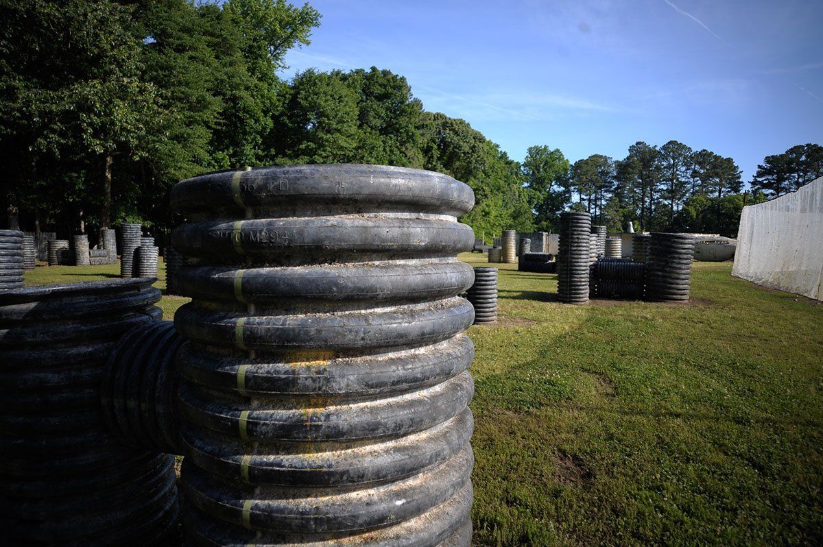 A bunch of tires are stacked on top of each other in a field.