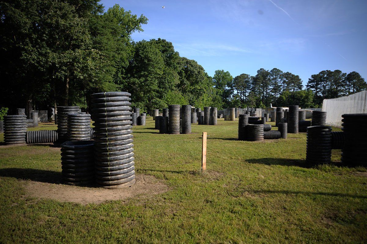 Hyperball Field - side view A paintball field with a lot of barrels and trees in the background.