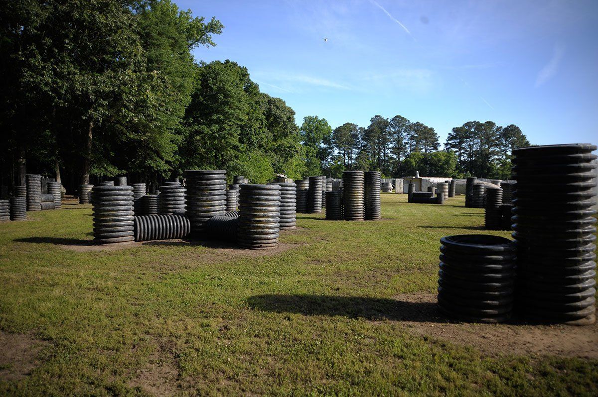A paintball field with lots of barrels and trees in the background.