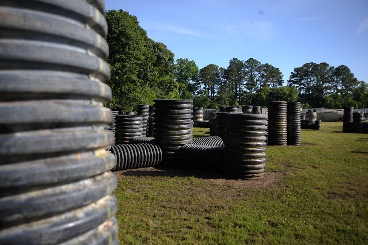 A paintball field with a lot of barrels and trees in the background.